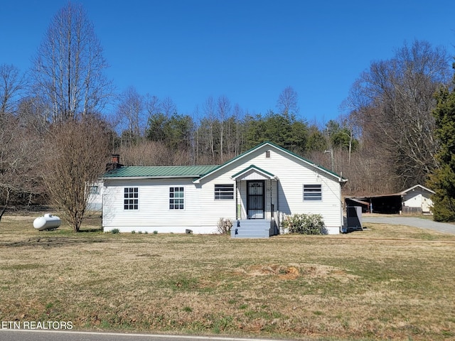 view of front of home featuring a front yard, metal roof, and a chimney