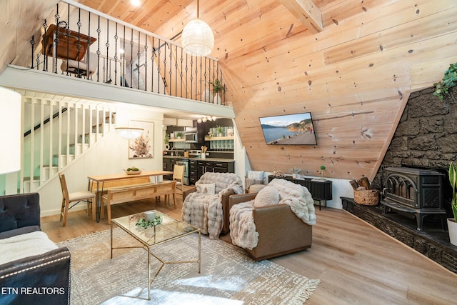 living room featuring wooden ceiling, wooden walls, wood finished floors, stairs, and a wood stove