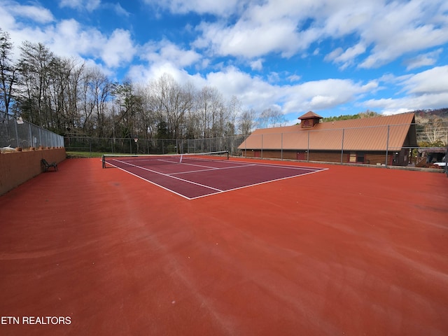 view of tennis court with community basketball court and fence