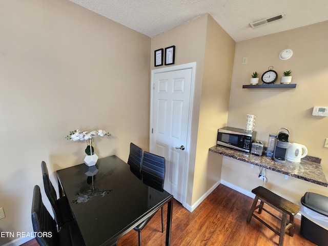 dining space with dark wood-style floors, baseboards, visible vents, and a textured ceiling