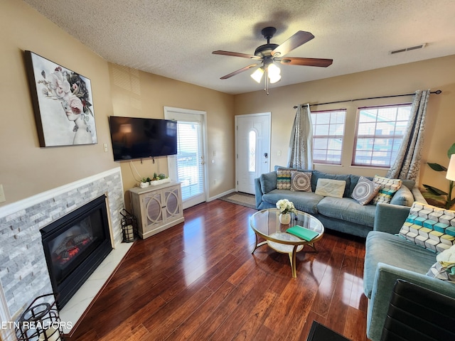 living area with visible vents, a fireplace with flush hearth, ceiling fan, wood finished floors, and a textured ceiling