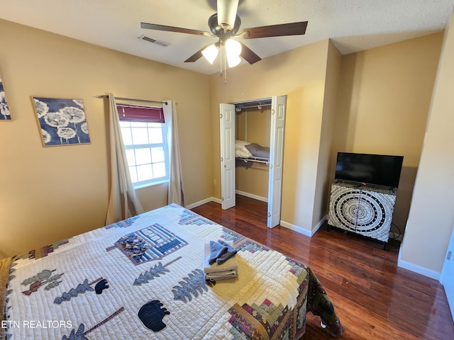 bedroom with baseboards, visible vents, a ceiling fan, wood finished floors, and a closet