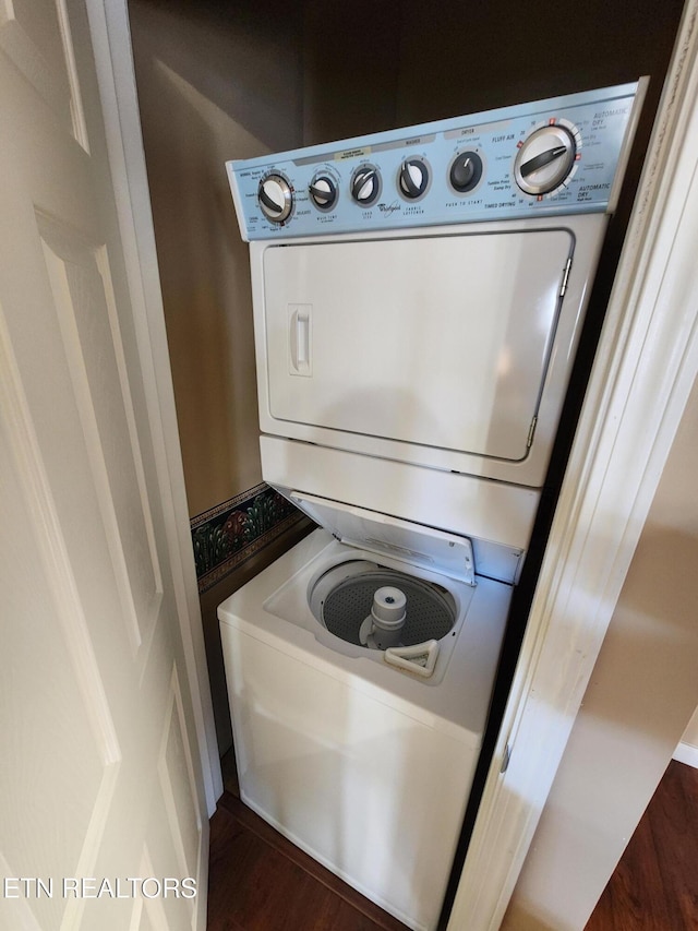 laundry area with laundry area, stacked washer / drying machine, and wood finished floors