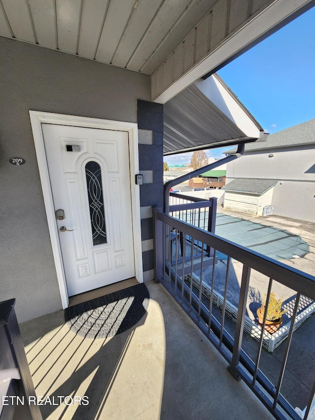 property entrance featuring a balcony and stucco siding