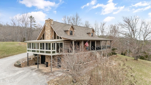 chalet / cabin featuring a chimney, central AC unit, a front yard, a sunroom, and driveway