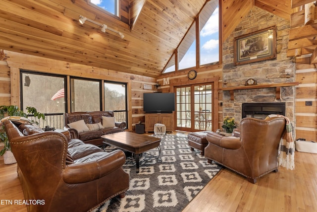 living area featuring wood ceiling, wood-type flooring, wood walls, and a stone fireplace