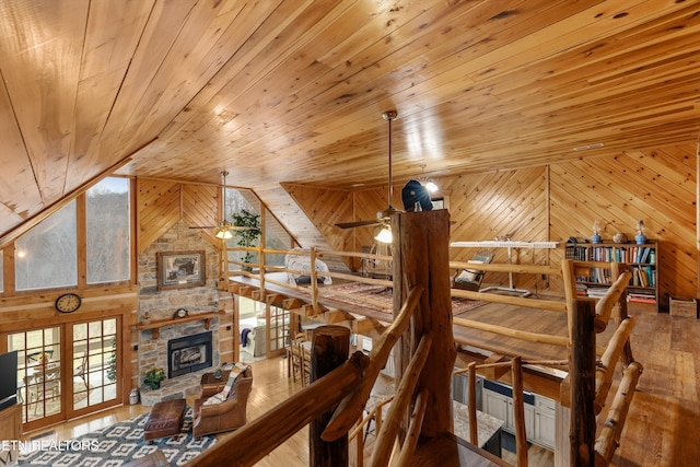 interior space with wooden ceiling, hardwood / wood-style flooring, wooden walls, and a stone fireplace