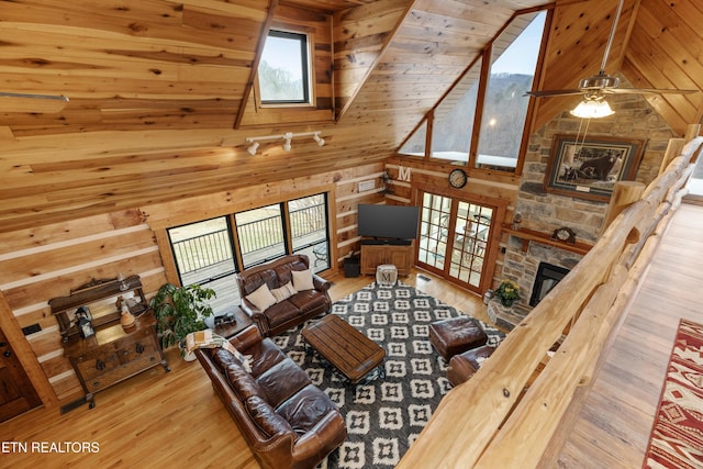 living room featuring high vaulted ceiling, wooden walls, a fireplace, wood finished floors, and wood ceiling