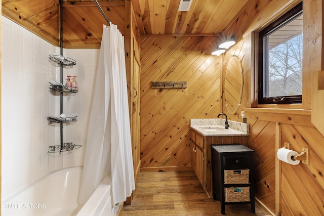 bathroom featuring wooden walls, wood ceiling, wood finished floors, shower / tub combo with curtain, and vanity