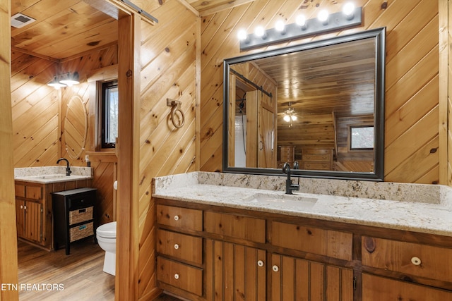 bathroom with wooden walls, toilet, wooden ceiling, wood finished floors, and vanity