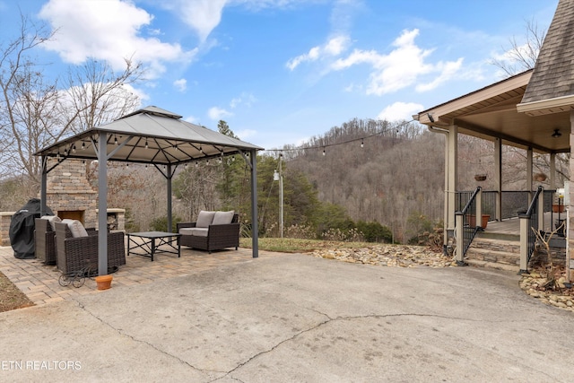 view of patio / terrace with a gazebo, an outdoor living space with a fireplace, and a grill