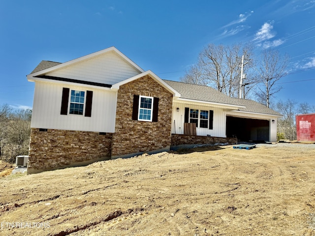 ranch-style home with central AC, brick siding, an attached garage, and roof with shingles