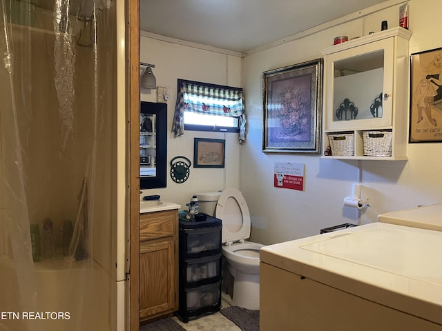 full bath with tile walls, toilet, washer and clothes dryer, and vanity