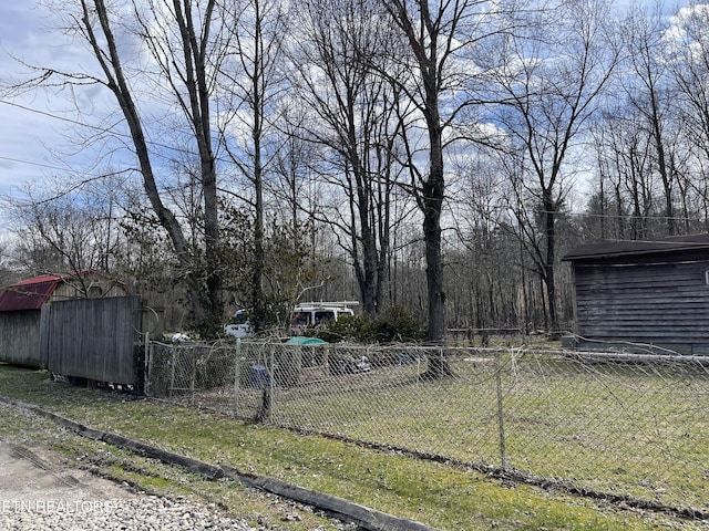 view of yard with fence, an outdoor structure, and a shed