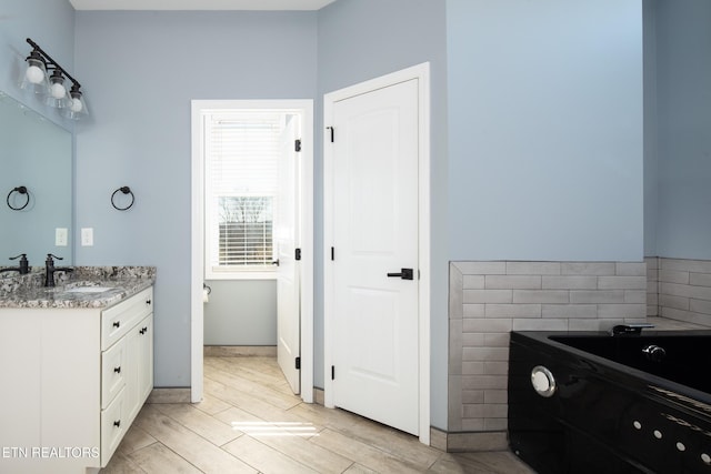 bathroom featuring wood tiled floor, a garden tub, and vanity