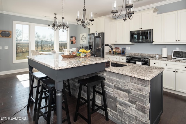 kitchen with dark wood finished floors, ornamental molding, a kitchen island with sink, black appliances, and a sink