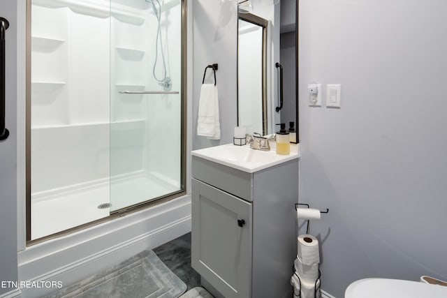 full bath with a stall shower, baseboards, vanity, and toilet