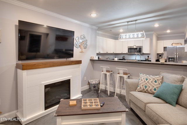 living room with ornamental molding, recessed lighting, a glass covered fireplace, and baseboards