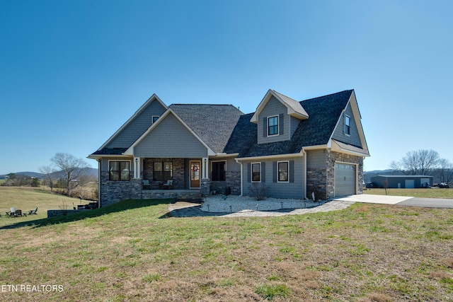 view of front of property featuring covered porch, an attached garage, a front yard, stone siding, and driveway