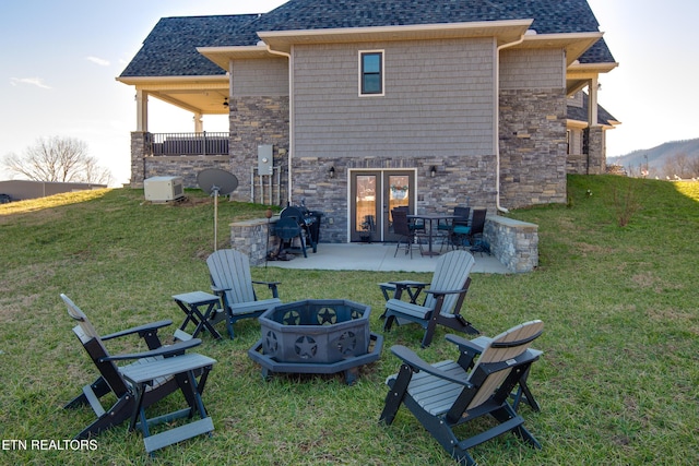 back of house with a patio area, a yard, a fire pit, and roof with shingles