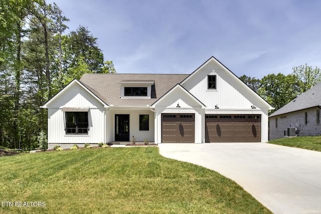 modern farmhouse style home with a shingled roof, a front yard, concrete driveway, and central air condition unit