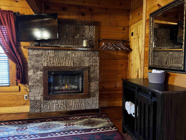 interior space featuring dark wood-type flooring, wood walls, and a glass covered fireplace