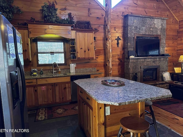 kitchen with wood walls, a sink, refrigerator with ice dispenser, and dishwasher