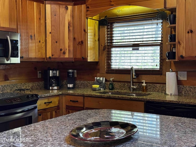 kitchen featuring black appliances, dark stone countertops, brown cabinets, and a sink