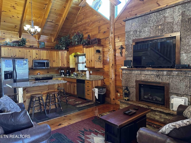 living room with dark wood finished floors, a glass covered fireplace, wood ceiling, wooden walls, and beamed ceiling