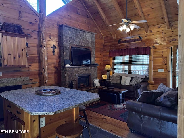 living room with wooden ceiling, wooden walls, a large fireplace, and beam ceiling