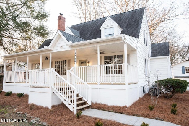 view of front of house featuring covered porch, ceiling fan, a shingled roof, and a chimney