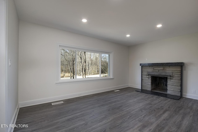 unfurnished living room featuring dark wood finished floors, recessed lighting, a fireplace, and baseboards