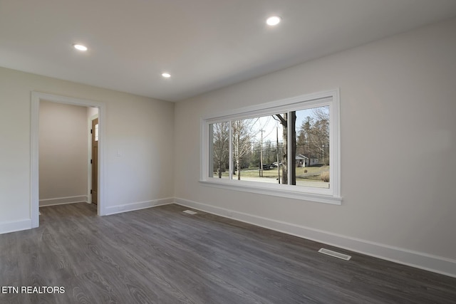 spare room featuring dark wood-type flooring, recessed lighting, baseboards, and visible vents