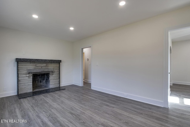 unfurnished living room with recessed lighting, a fireplace, baseboards, and wood finished floors