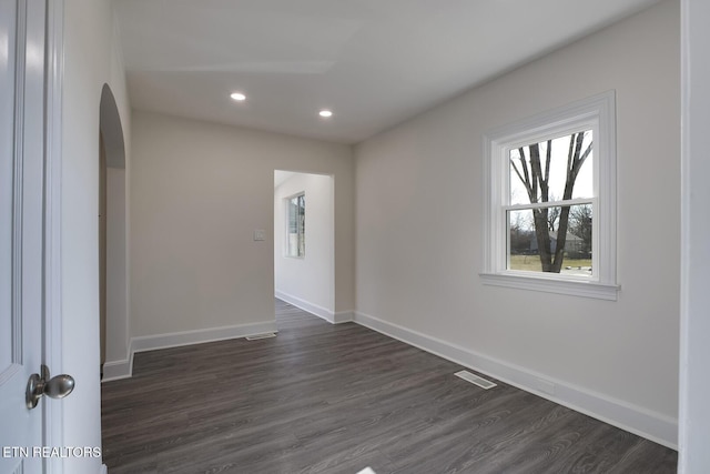 unfurnished room with visible vents, baseboards, and dark wood-type flooring