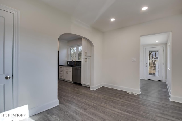 interior space with a sink, arched walkways, dark wood finished floors, and recessed lighting