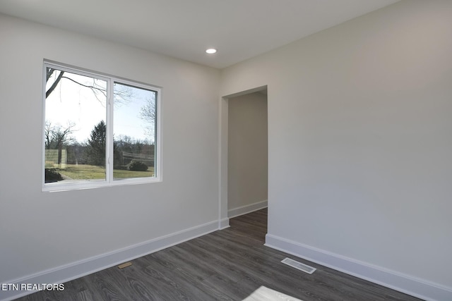 empty room with baseboards, a healthy amount of sunlight, and dark wood-style flooring