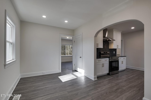 kitchen featuring electric range, dark wood-style flooring, white cabinetry, wall chimney exhaust hood, and backsplash