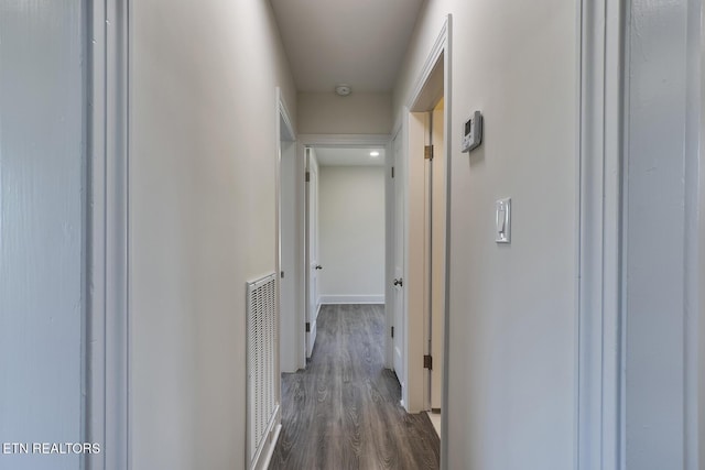 hall featuring dark wood-type flooring, baseboards, and visible vents