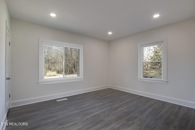 spare room featuring visible vents, recessed lighting, dark wood-type flooring, and baseboards