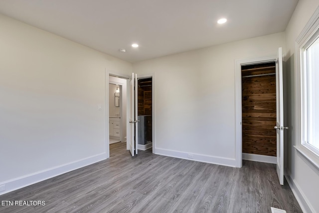 unfurnished bedroom featuring recessed lighting, wood finished floors, and baseboards