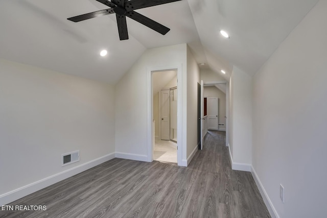 unfurnished bedroom with visible vents, baseboards, lofted ceiling, wood finished floors, and ensuite bath