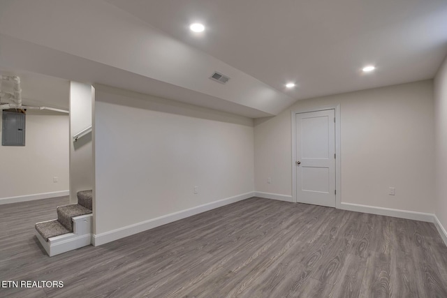 finished basement featuring visible vents, electric panel, dark wood finished floors, stairway, and baseboards