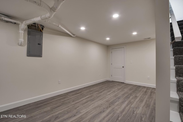 finished basement with electric panel, wood finished floors, recessed lighting, baseboards, and stairs