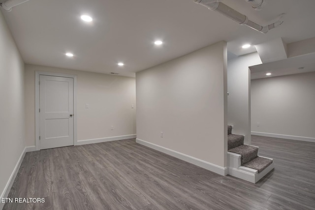 below grade area featuring recessed lighting, stairway, baseboards, and wood finished floors