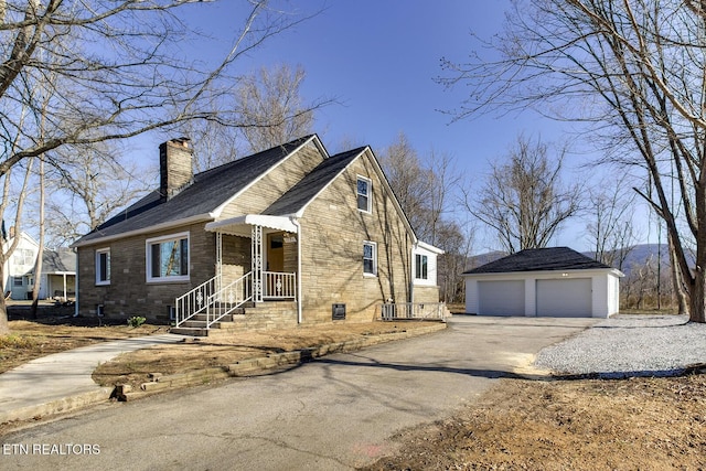 view of front of home featuring a garage, a chimney, and an outdoor structure