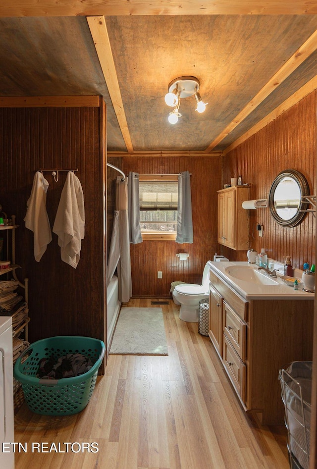 full bathroom featuring toilet, shower / bath combo, wood walls, vanity, and wood finished floors