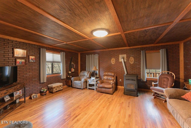 living area featuring a wood stove, brick wall, and wood finished floors