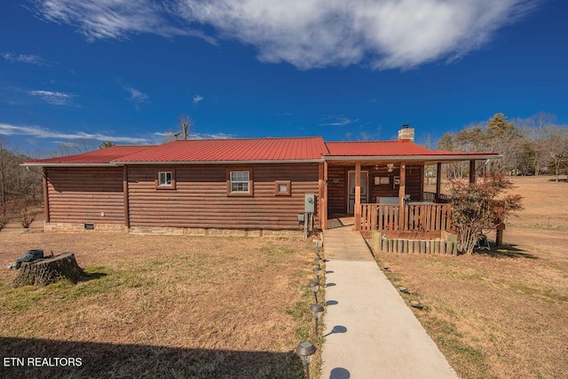 chalet / cabin featuring metal roof, a chimney, and a front yard