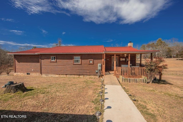 rustic home with a front yard, metal roof, and a chimney